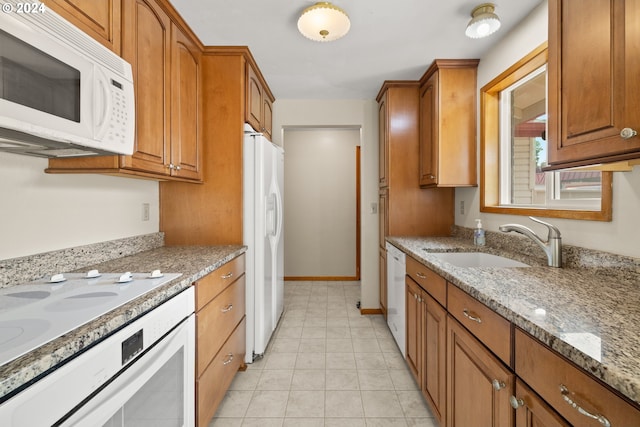 kitchen featuring white appliances, light tile patterned floors, light stone countertops, and sink