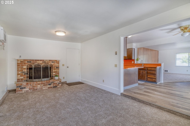 422 E 5th St, Coquille, OR 97423 - unfurnished living room with light carpet, ceiling fan, baseboards, a brick fireplace, and light wood-style flooring