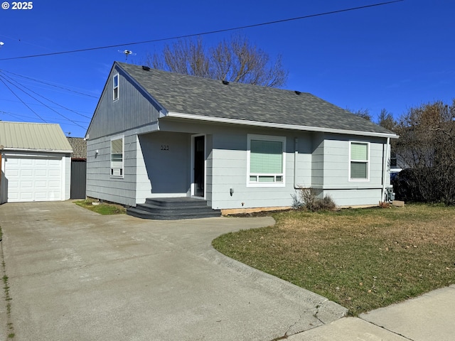 view of front of home with a front yard, roof with shingles, an outdoor structure, and driveway