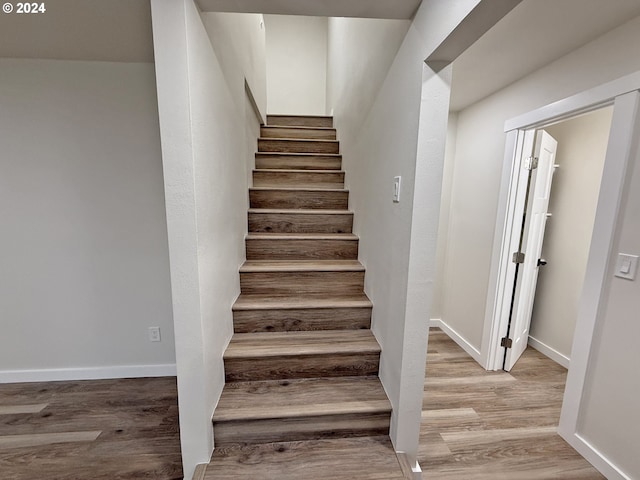 staircase featuring wood finished floors and baseboards