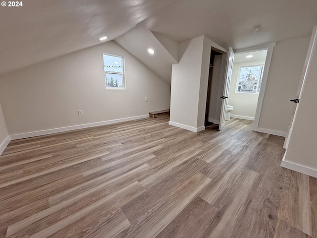 bonus room featuring vaulted ceiling, light wood finished floors, and baseboards