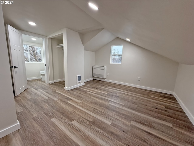 additional living space with recessed lighting, visible vents, vaulted ceiling, wood finished floors, and baseboards