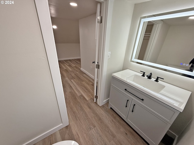 bathroom with recessed lighting, wood finished floors, vanity, and baseboards