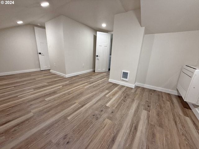 additional living space with vaulted ceiling, light wood finished floors, recessed lighting, and baseboards