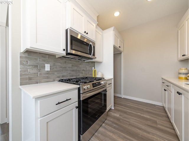 kitchen featuring decorative backsplash, appliances with stainless steel finishes, white cabinetry, and dark hardwood / wood-style flooring