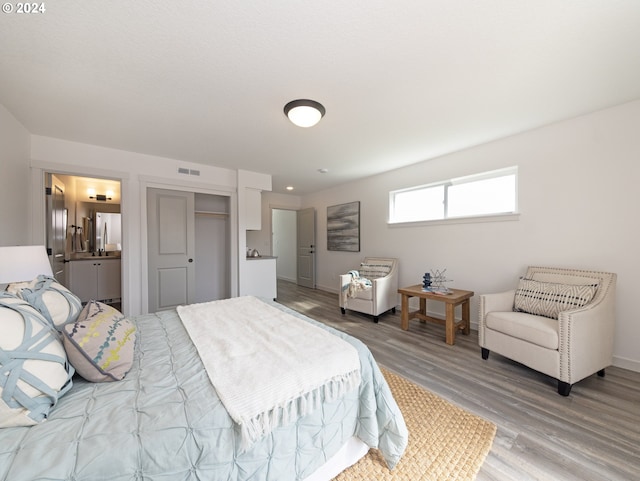 bedroom with connected bathroom, a closet, light hardwood / wood-style floors, and white refrigerator