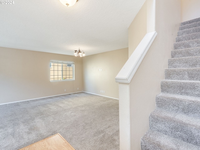 stairway featuring baseboards, a notable chandelier, a textured ceiling, and carpet