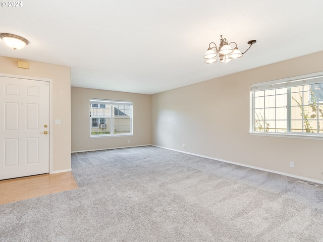 unfurnished living room with an inviting chandelier and light carpet