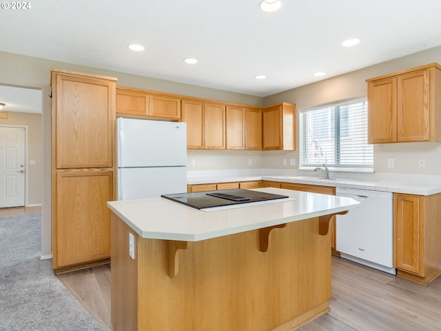 kitchen with white appliances, a breakfast bar area, a center island, and light hardwood / wood-style floors