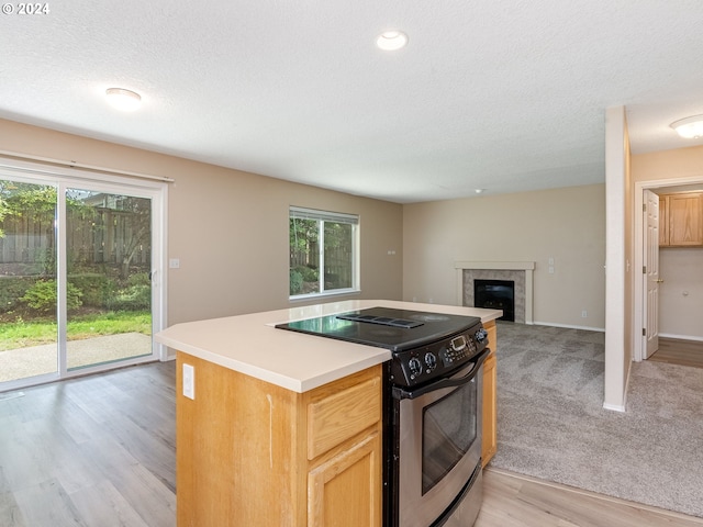 kitchen featuring light wood-type flooring, a fireplace, plenty of natural light, and range with electric stovetop