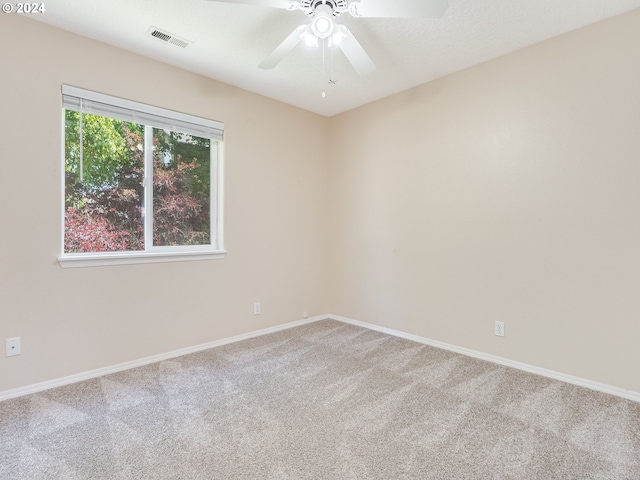 spare room featuring a textured ceiling, ceiling fan, and light carpet