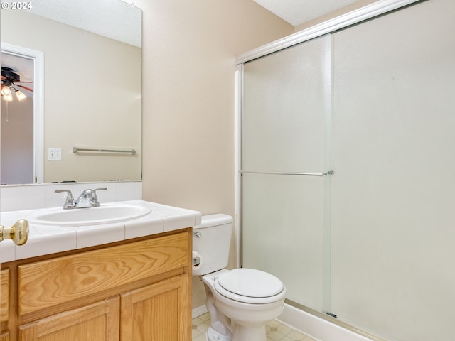 bathroom featuring vanity, toilet, walk in shower, and ceiling fan