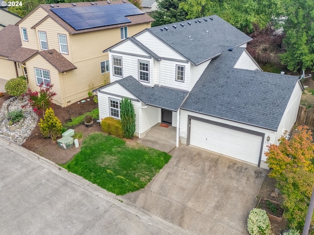 view of front of property featuring a front yard, driveway, a garage, and roof with shingles