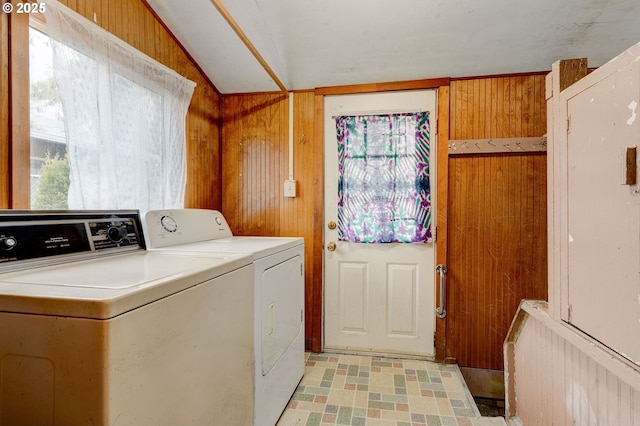 clothes washing area featuring washer and clothes dryer, plenty of natural light, and wooden walls