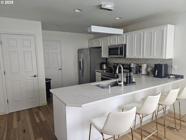 4024 NE 166th Ave, Vancouver, WA 98682 - kitchen featuring appliances with stainless steel finishes, a peninsula, tasteful backsplash, light stone counters, and white cabinets