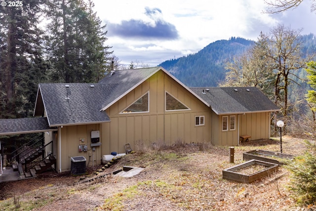 back of property featuring central AC unit, board and batten siding, and a shingled roof