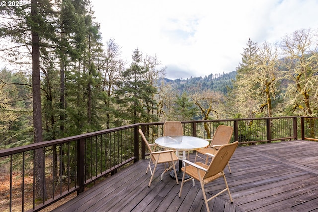 wooden deck with outdoor dining area and a view of trees