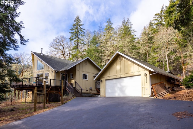 chalet / cabin featuring stairway, roof with shingles, a deck, a detached garage, and board and batten siding