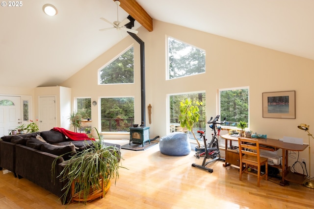 living room with beam ceiling, a wood stove, wood finished floors, and a wealth of natural light