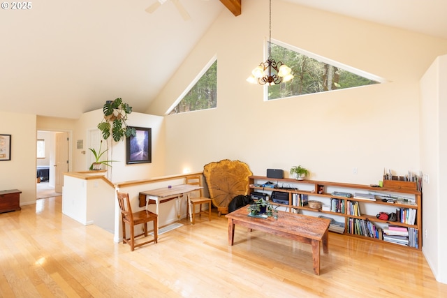 sitting room with beamed ceiling, high vaulted ceiling, an inviting chandelier, and wood finished floors