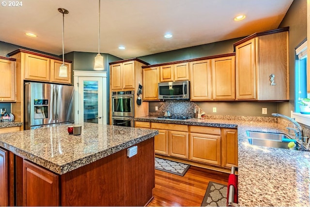 kitchen featuring pendant lighting, stainless steel appliances, a kitchen island, sink, and dark wood-type flooring