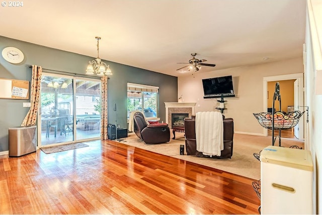 living room with ceiling fan with notable chandelier and light wood-type flooring