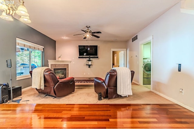 living room featuring light hardwood / wood-style flooring, ceiling fan, and washer / dryer