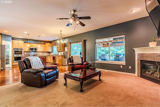 living room with light wood-type flooring and ceiling fan with notable chandelier