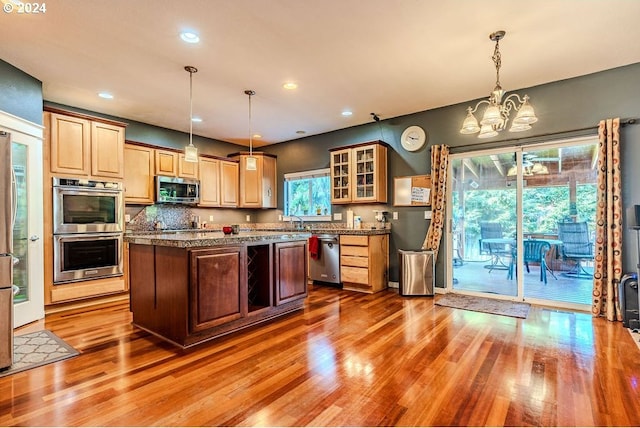 kitchen featuring hardwood / wood-style floors, a kitchen island, stainless steel appliances, and an inviting chandelier