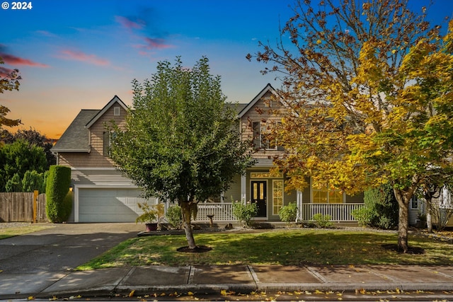 obstructed view of property featuring a porch, a yard, and a garage