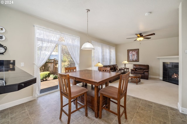 dining area with carpet, a tiled fireplace, and ceiling fan