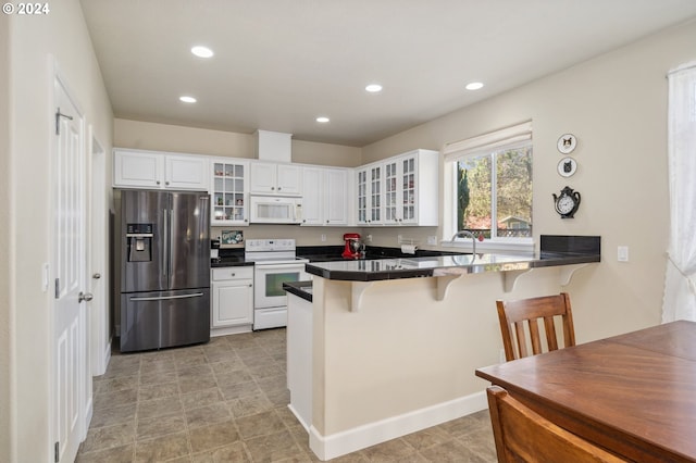 kitchen with a kitchen breakfast bar, white cabinets, kitchen peninsula, and white appliances