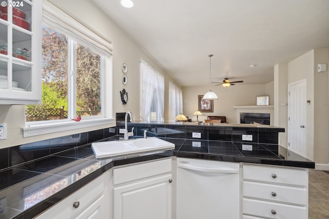 kitchen with dishwasher, sink, white cabinets, a fireplace, and ceiling fan