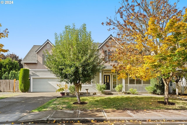 view of property hidden behind natural elements featuring a garage, a front lawn, and a porch