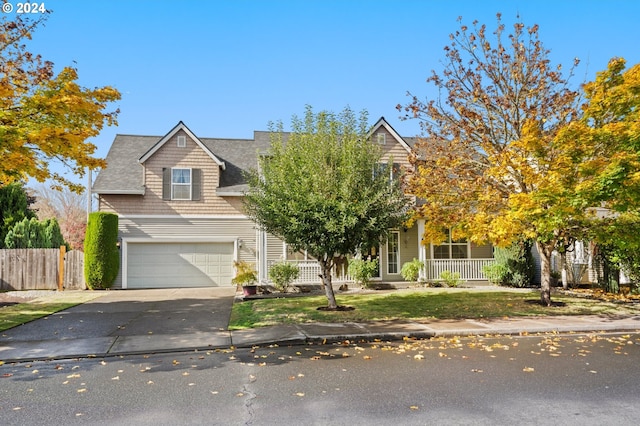 view of property hidden behind natural elements featuring a porch and a garage