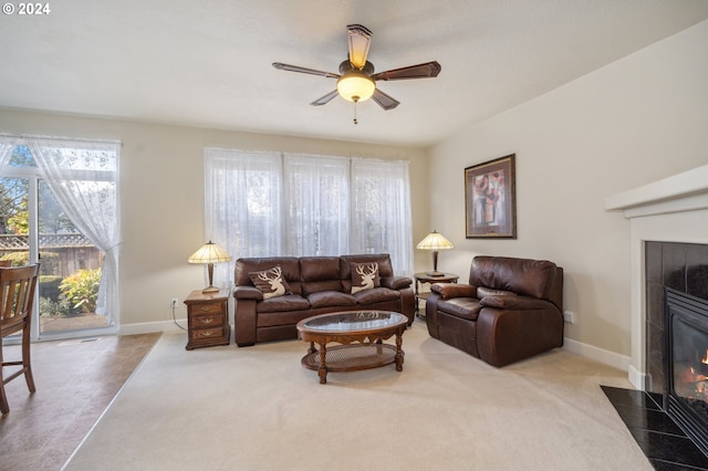 carpeted living room with a tiled fireplace and ceiling fan