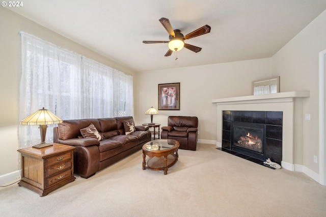 living room featuring a tiled fireplace, carpet flooring, and ceiling fan