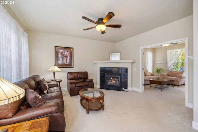 carpeted living room featuring a tiled fireplace and ceiling fan