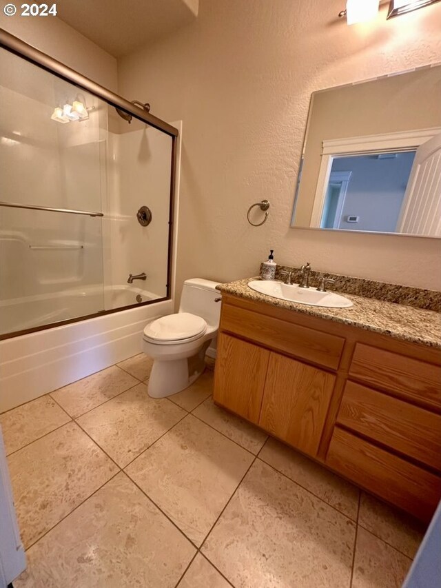 full bathroom featuring bath / shower combo with glass door, vanity, toilet, and tile patterned flooring