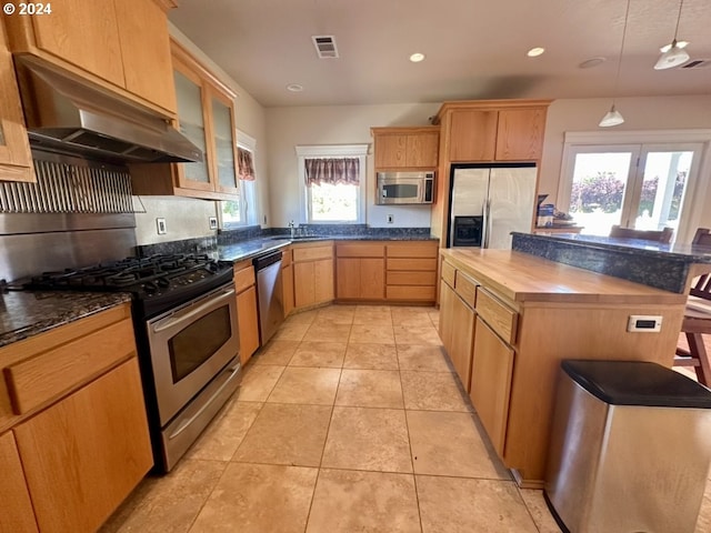 kitchen featuring pendant lighting, wooden counters, stainless steel appliances, a center island, and light tile patterned flooring