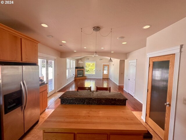 kitchen with stainless steel fridge, decorative light fixtures, light hardwood / wood-style flooring, and a wealth of natural light