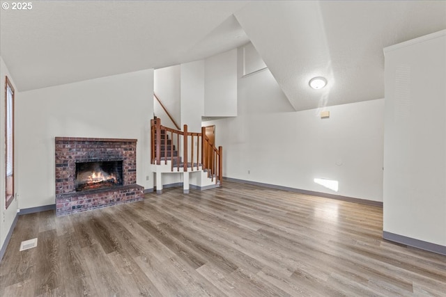 2427 SW 218th Dr, Beaverton, OR 97003 - unfurnished living room with lofted ceiling, wood finished floors, stairway, a fireplace, and baseboards