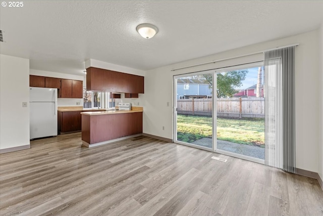 2427 SW 218th Dr, Beaverton, OR 97003 - kitchen with freestanding refrigerator, a peninsula, light wood-style flooring, light countertops, and a textured ceiling