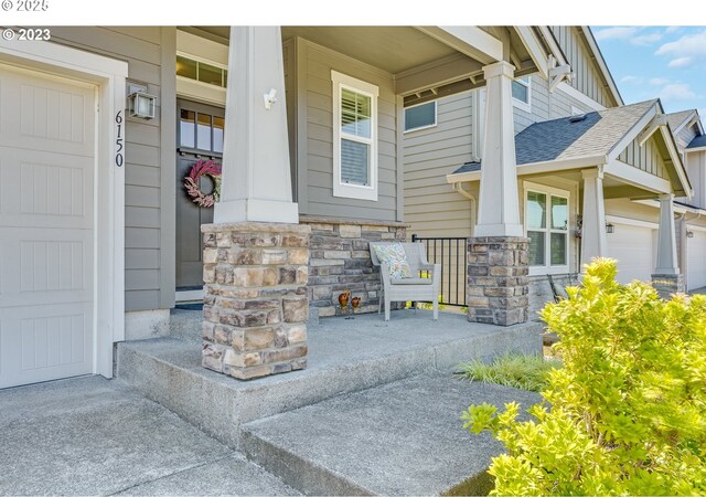 doorway to property featuring a garage, a porch, board and batten siding, and roof with shingles