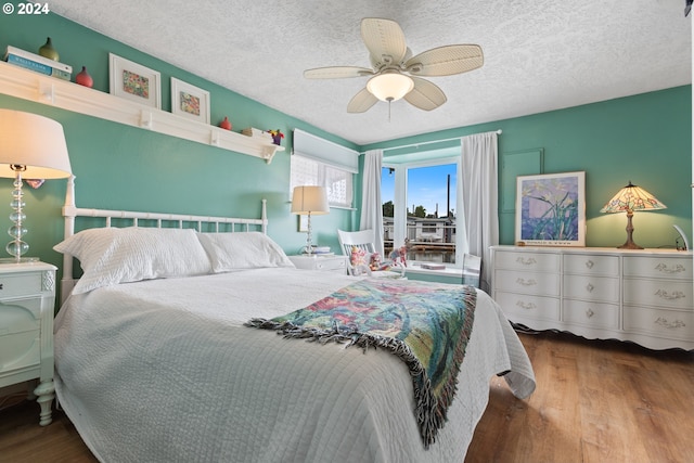 bedroom with ceiling fan, wood-type flooring, and a textured ceiling