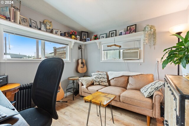 home office with vaulted ceiling, radiator heating unit, and light hardwood / wood-style floors