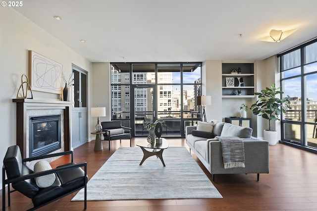 living room featuring dark hardwood / wood-style floors, a fireplace, floor to ceiling windows, and built in shelves