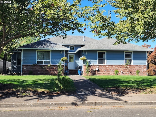 ranch-style home with brick siding, a shingled roof, and a front yard