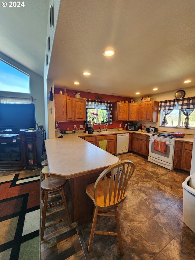 kitchen with white appliances, kitchen peninsula, sink, and a breakfast bar area