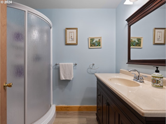 bathroom with walk in shower, vanity, and hardwood / wood-style floors